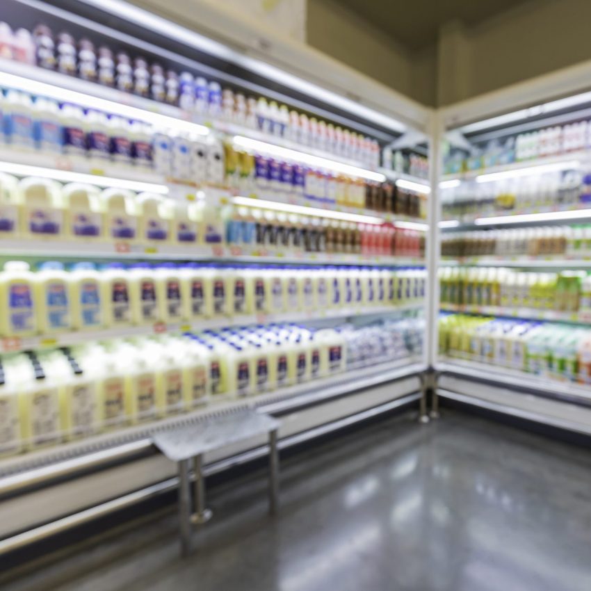 The defocused blur of supermarket drink shelves with dairy products. Blur background with bokeh. Defocused image