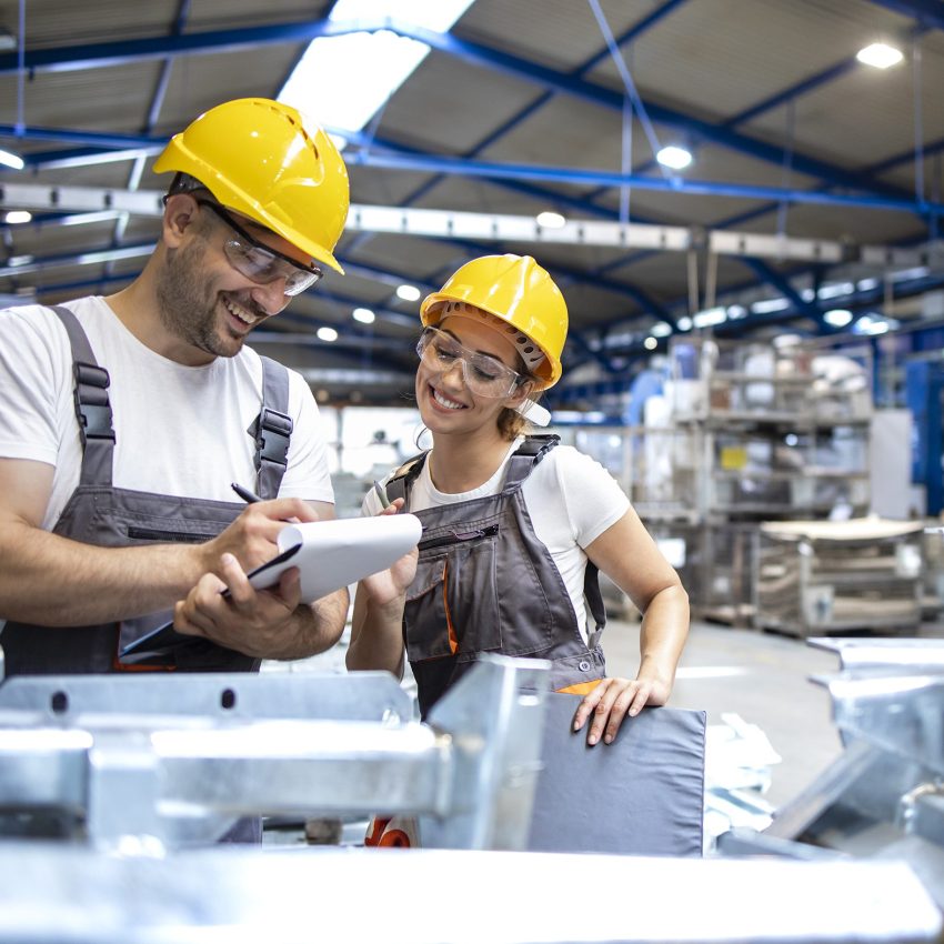 Factory workers checking quality of products in large industrial hall.