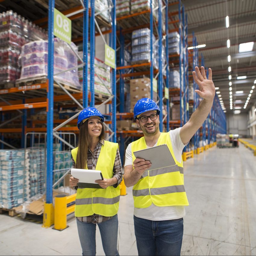 Warehouse workers checking organization and distribution of products in large storage area.